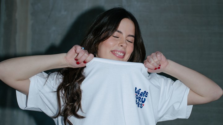 En tjej visar upp sin t-shirt med texten We are orubros