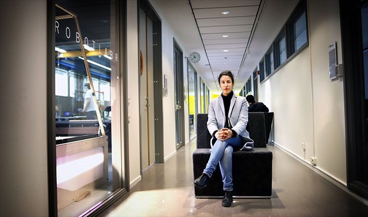 Amy Loutfi sitting with her legs crossed on a chair in the hallway outside the robot lab.