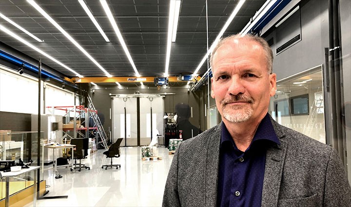 Göran Backlund standing in the robot lab with various equipment in the background.