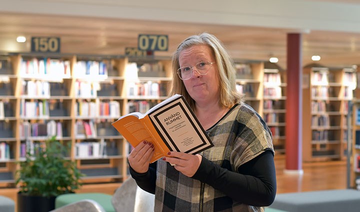 Foto på Maria Axinge som håller i boken "Använd rummet"