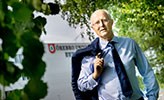 Johan Schnürer står framför Örebro universitet. Han har kavajen slängd över ena axeln.