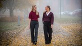 Elin Vimefall och Ebba Löfgren går på en gata. Det är höst med gula löv på vägen och dimma. 