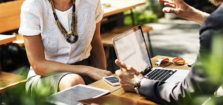 A woman and a man in a meeting, a laptop is on the desk.