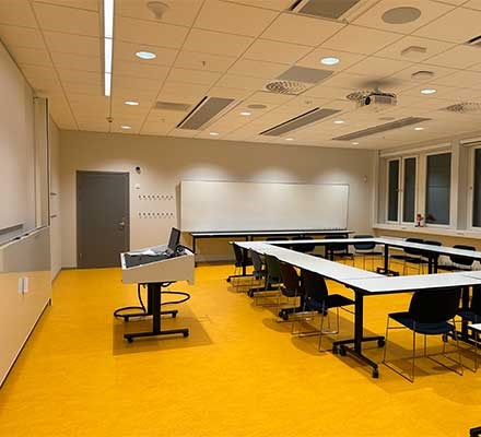 Vy X4423 Bord och stolar möblerade i ett U. Ett teknikbord syns också.