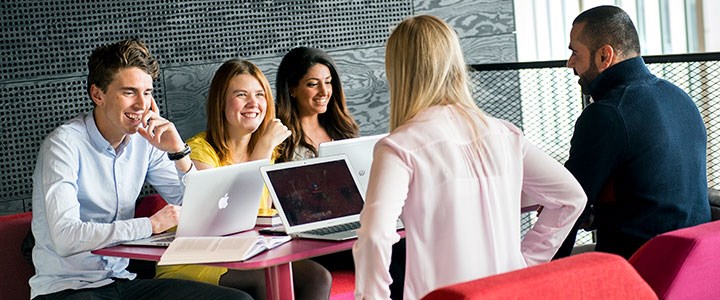 Fem studenter sitter och pluggar och skrattar i Novahuset 
