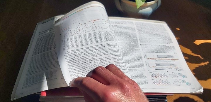 Photo of a hand turning a page in a journal.