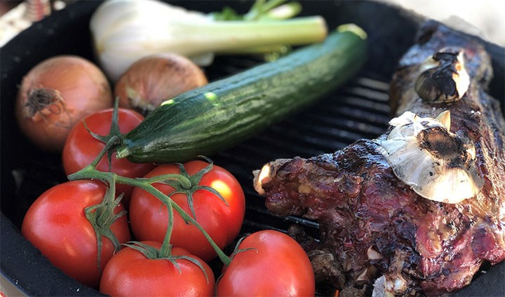 Bilden visar en grill där det ligger fänkål, gurka, tomater och lamm.