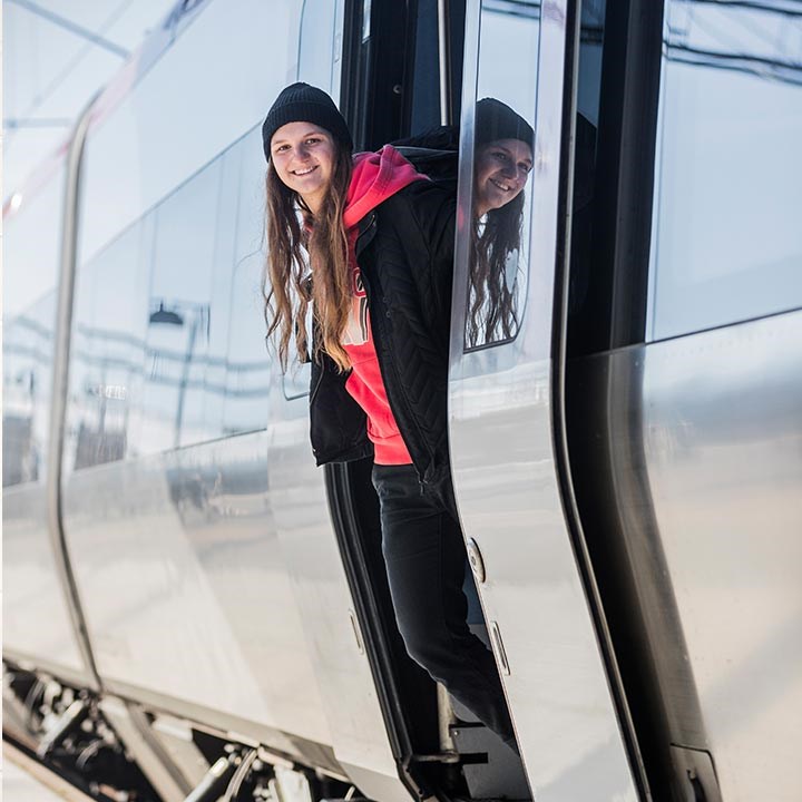 En tjej som tittar ut från en dörr på ett tåg
