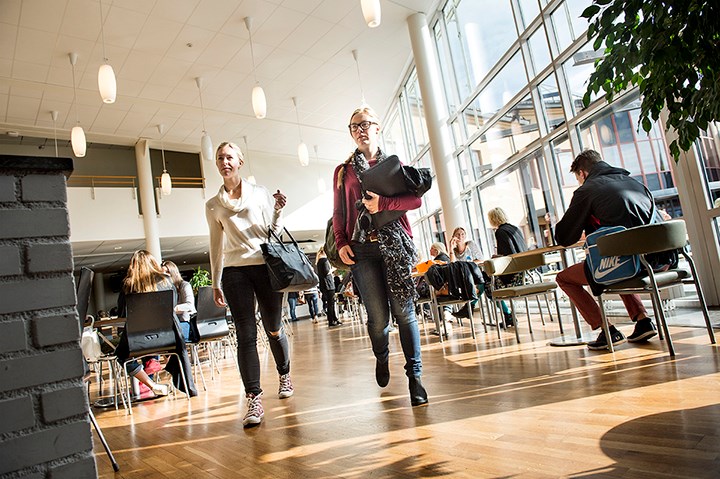 Några studenter går förbi ett stort glasfönster.