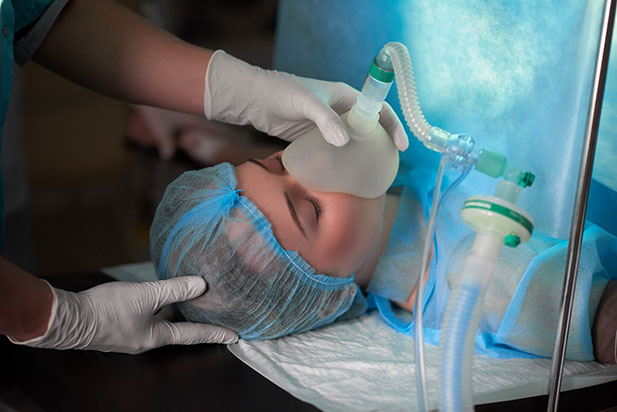 Person on operating table with anesthesia mask on.
