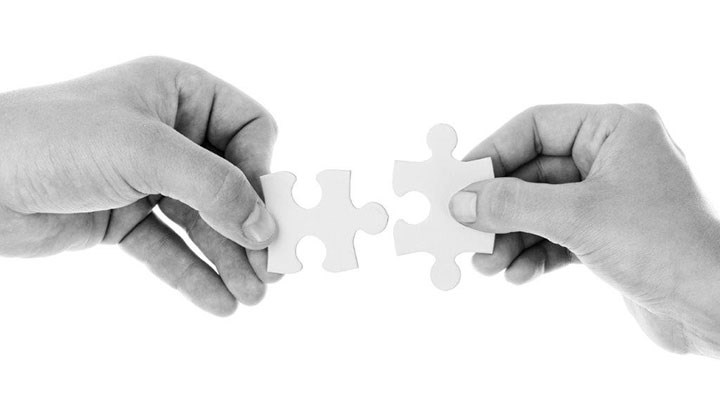 Two hands, each holding a piece of a puzzle