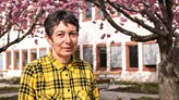 n person med en svart- och gulrandig skjorta står framför ett blommande körsbärsträd.