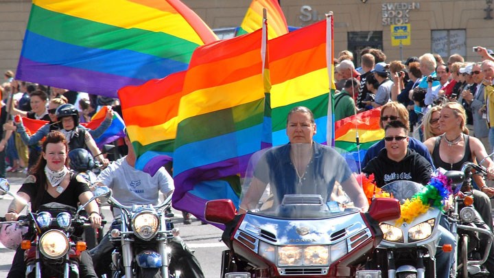 Människor går i en pride-parad med regnbågsflaggor.