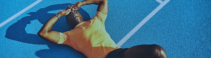 A man is lying and resting on a running track.