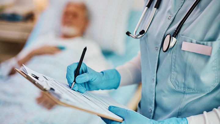 En vårdpersonal som antecknar vid en patient.