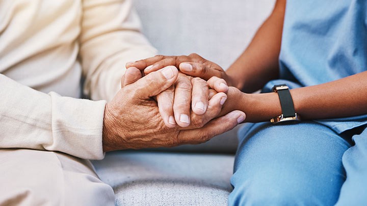 En vårdtagares och en vårdpersonals händer som möts.