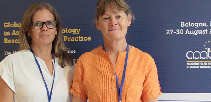 Maria Borgestig i vit blus och Cecilia Pettersson i orange blus framför konferensväggen