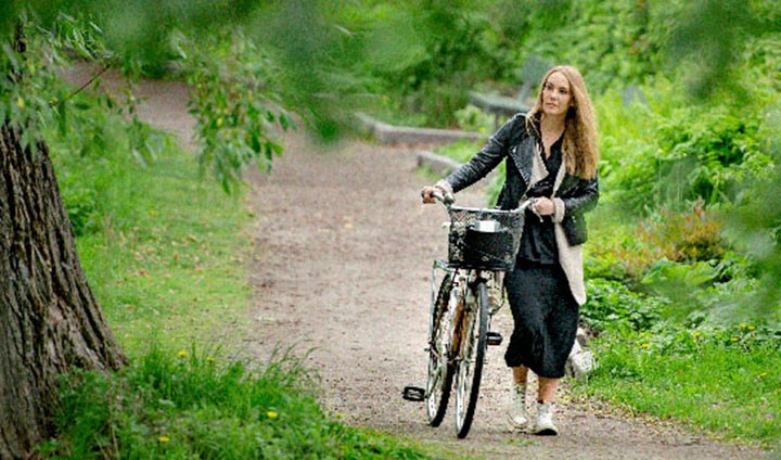 Kvinna leder en cykel på en skogsstig