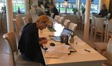 Forskare sitter en och en vid långa bord och skriver