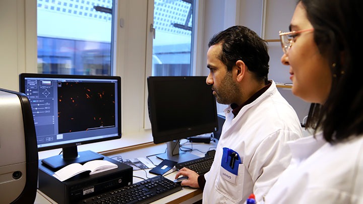 A man and a woman in hospital clothes are looking at a computer screen.