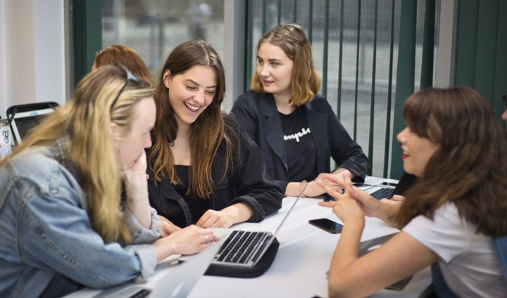 Elever som sitter vid en dator och ler