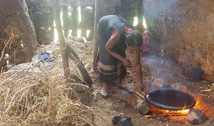 Kvinnir lagar mat över öppen eld i ett hus på den etipopiska landsbygden.