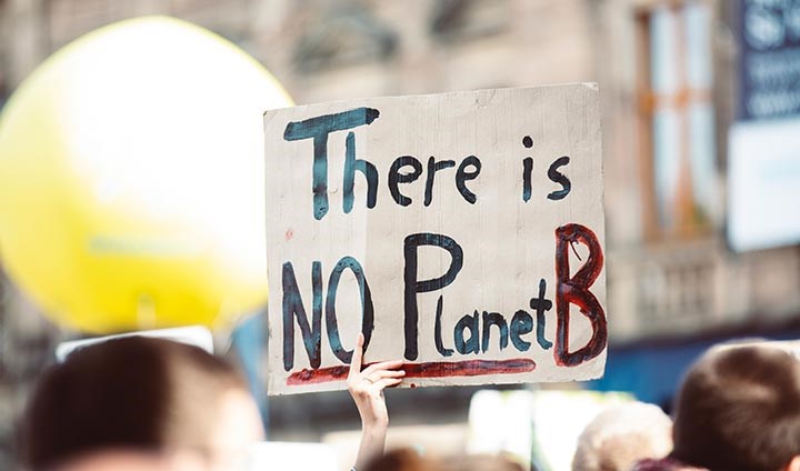 En hand som sträcker upp en skylt där det står "There is no Planet B"