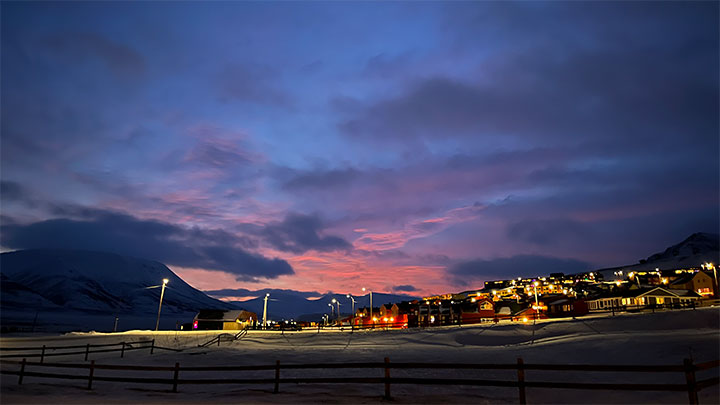 Lighted housing with a sunset sky.