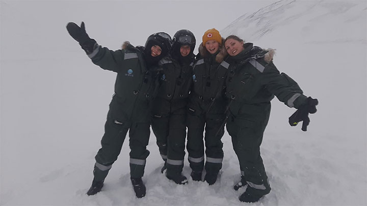 A group of students in winter clothes standing outside in the snow.