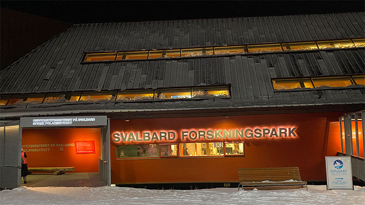 The entrance and brightly lit sign of the University Centre on Svalbard.