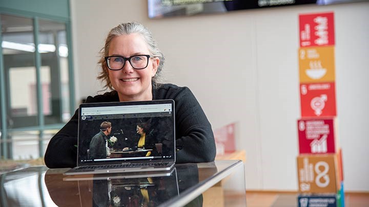 Karin Hedström bakom en datorskärm i foajén till Entréhuset.
