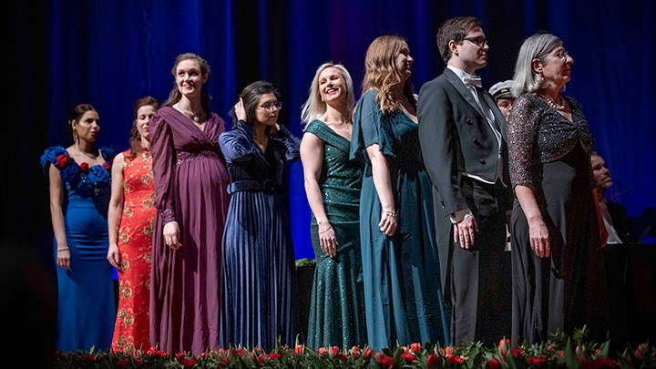 Doctoral graduates in a row on stage.