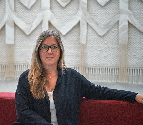 Jenny Alsarve sitter på en röd soffa.