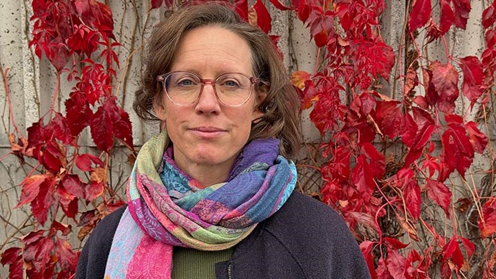 Lena Gunnarsson, in front of a wall of read autumn leaves.