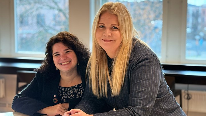 Två personer poserar framför ett fönster.