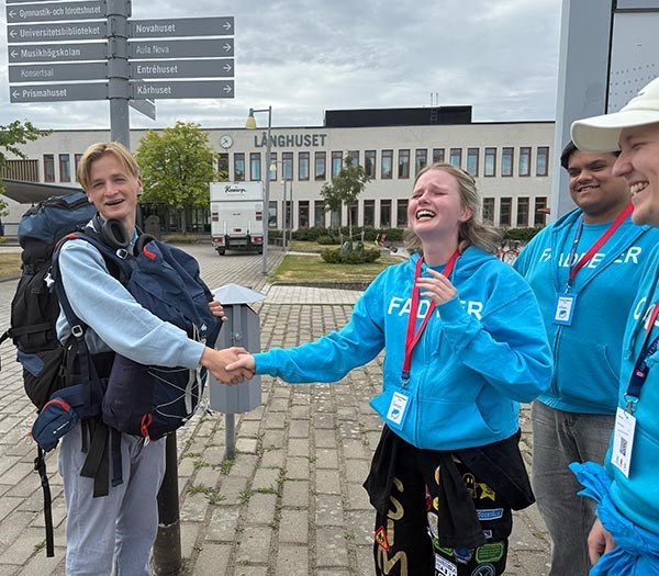 Fyra studenter, två som skakar hand.