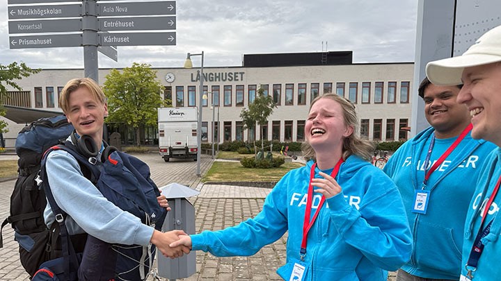 Fyra studenter, två som skakar hand.