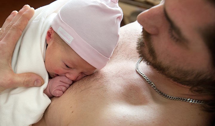 En pappa håller sin bebis mot bröstet..