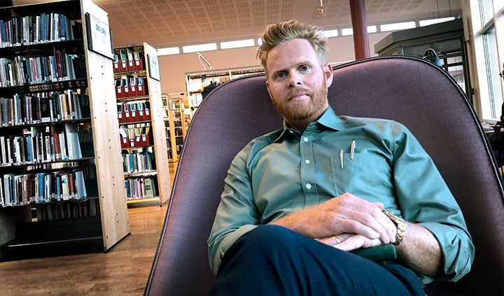 Henrik Andershed sitter i en fåtölj i ett bibliotek