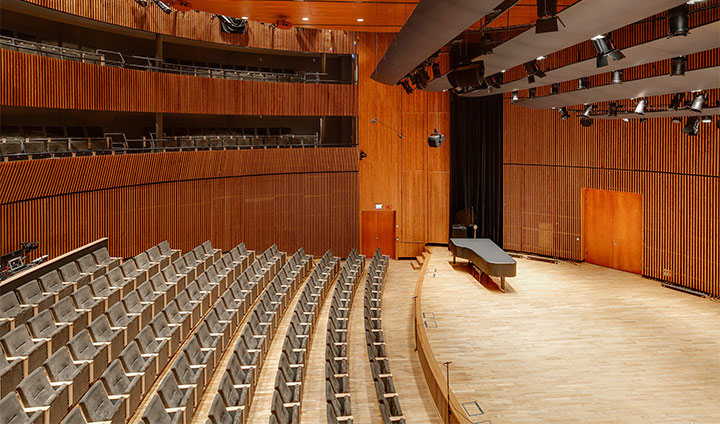 Interiör från konsertsalen med bänkrader och en scen.