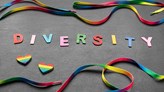 Färgglada bokstäver som bildar ordet ”DIVERSITY”, tillsammans med regnbågsband och hjärtan på mörk bakgrund.