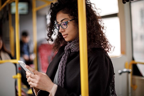 Kvinna på buss med mobilen i hand