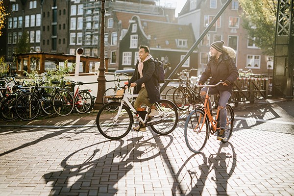 Två vänner som cyklar i Amsterdam