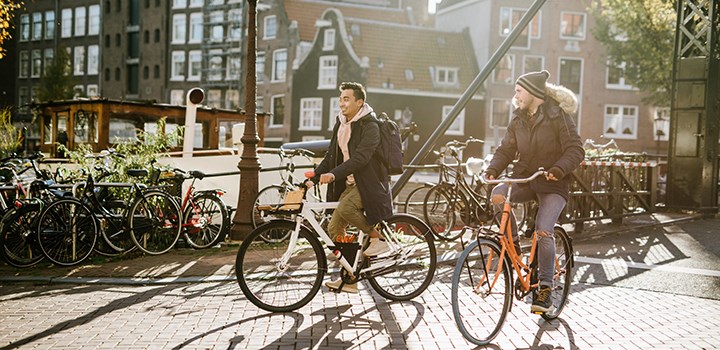 Två vänner cyklar i Amsterdam