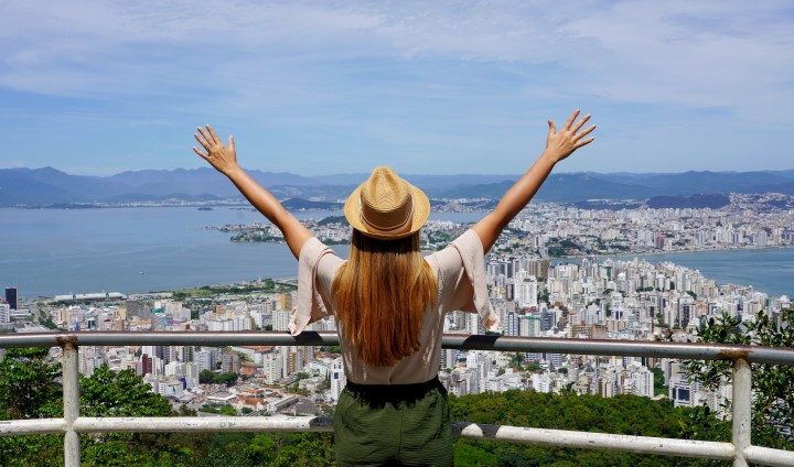 Tjej tittar på utsikt över Brasilien och sträcker upp båda armarna i luften