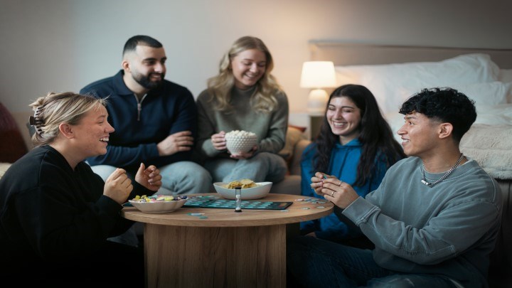 Studenter som sitter runt ett bord och skrattar samt spelar spel.