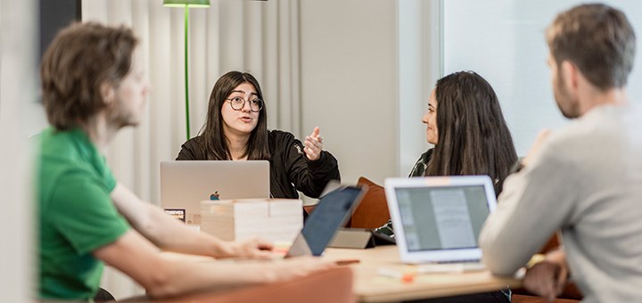 Fyra studenter sitter och diskuterar.