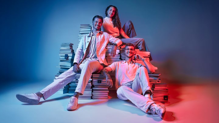 Tre studenter mot blå bakgrund.