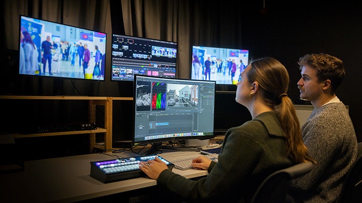 Två studenter sitter vid en dator och redigerar film.