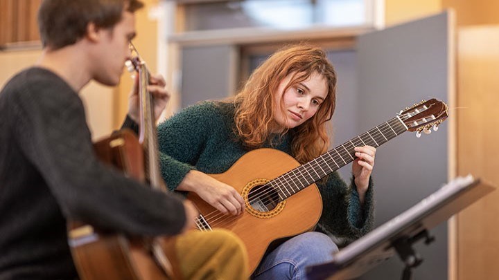 Två personer spelar akustisk guitarr.